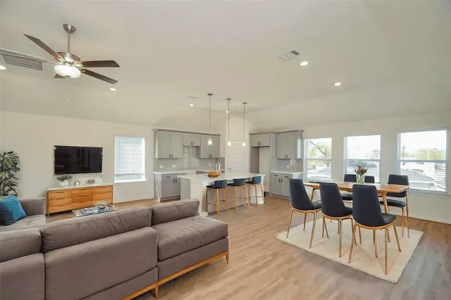 a living room with furniture kitchen view and a flat screen tv