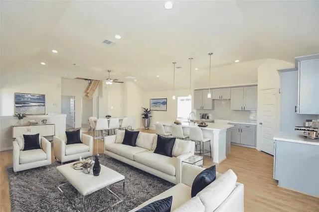 a living room with furniture a table and kitchen view