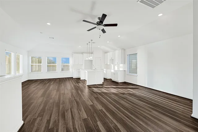 a view of empty room with wooden floor and ceiling fan