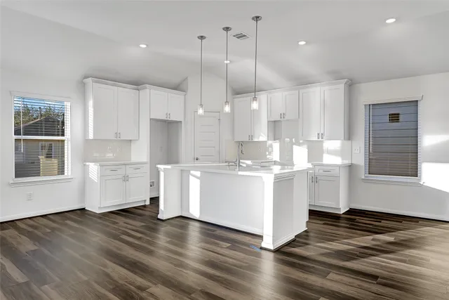 a kitchen with stainless steel appliances granite countertop a wooden floors and white cabinets