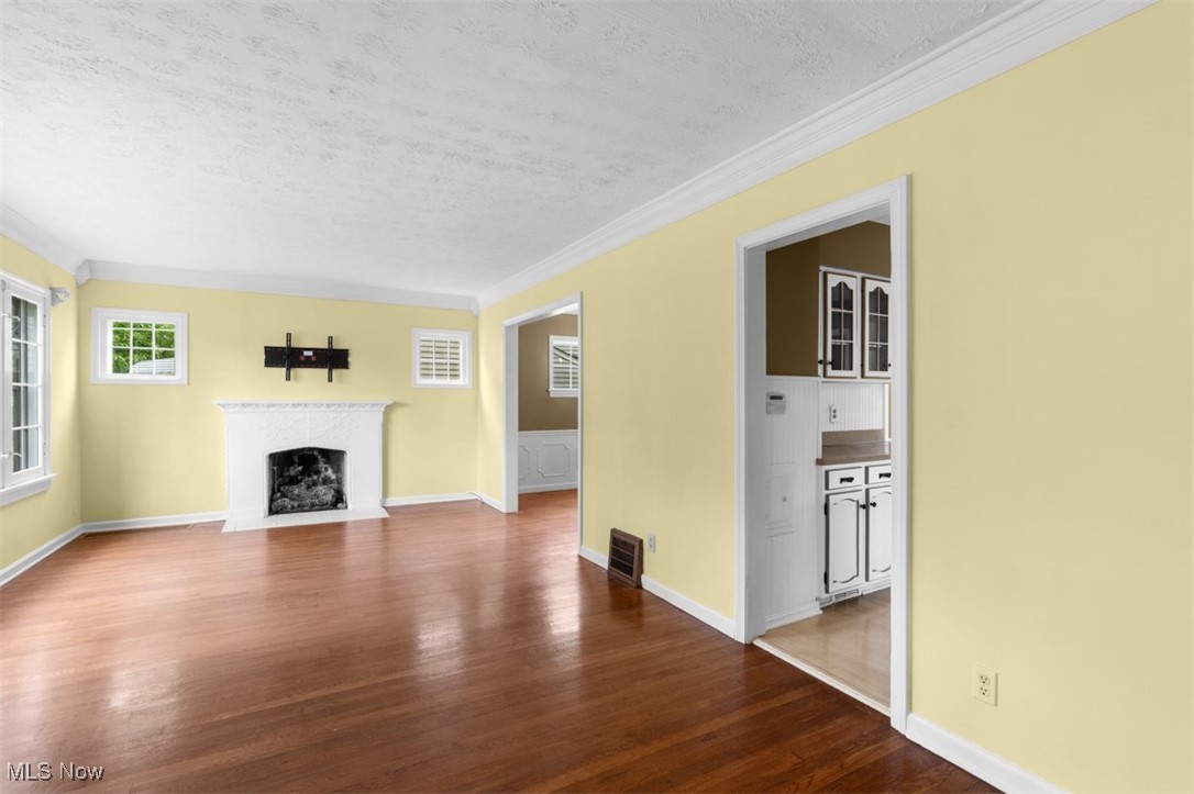 1492 Lyndhurst Road Lyndhurst, OH 44124 - Photo 4 of 32 Living room with a textured ceiling, a fireplace with hearth, dark wood flooring, crown molding, and baseboards