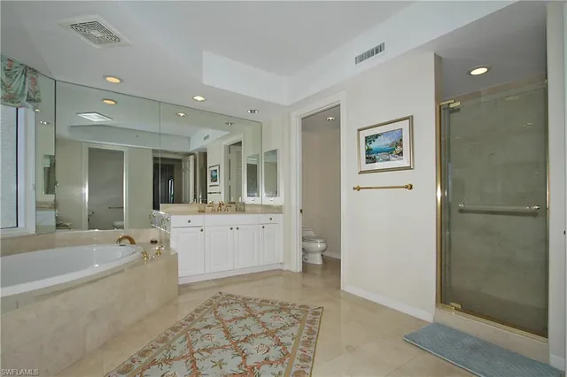 a large spacious bathroom with a tub shower and mirror