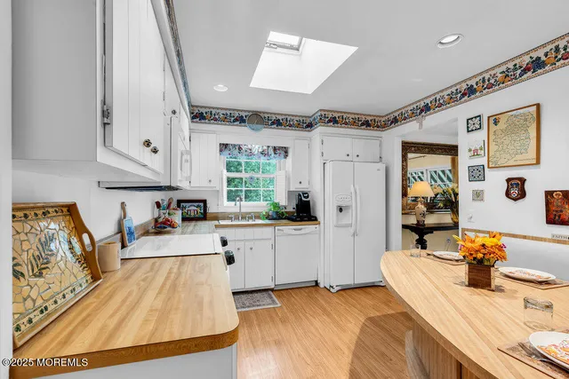 a large white kitchen with a stove a sink dishwasher and a fireplace with wooden floor