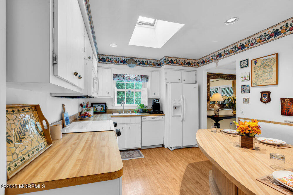 40 Brookside Lane Little Silver, NJ 07739 - Photo 14 of 43 a large white kitchen with a stove a sink dishwasher and a fireplace with wooden floor