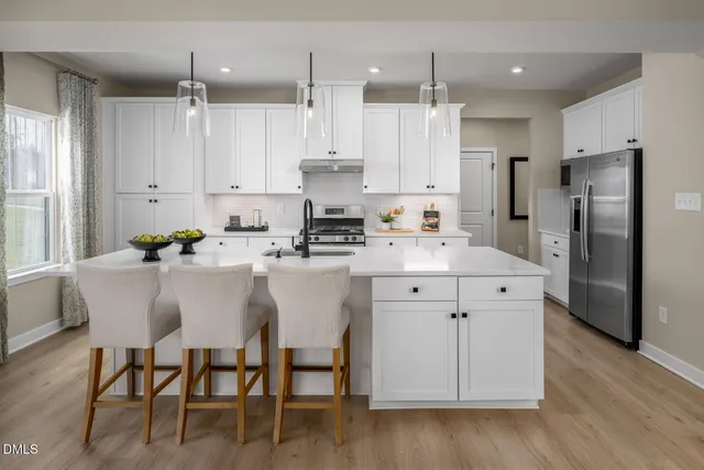 a kitchen with stainless steel appliances a dining table chairs microwave and sink