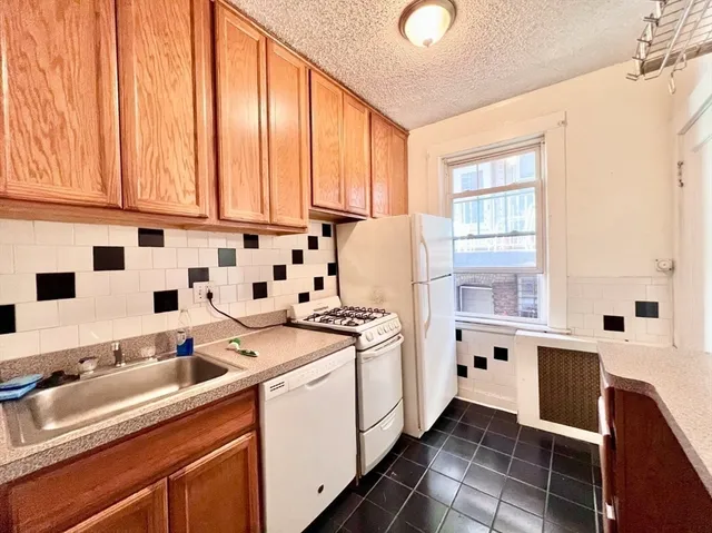 a kitchen with a sink a stove and white cabinets