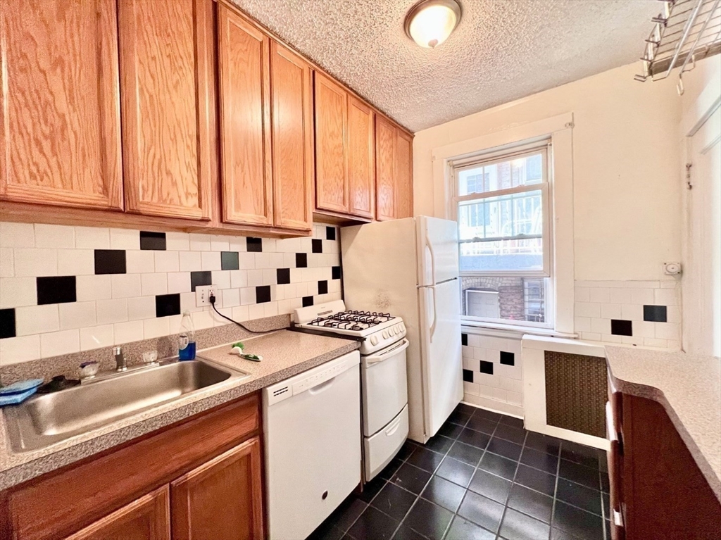 a kitchen with a sink a stove and white cabinets
