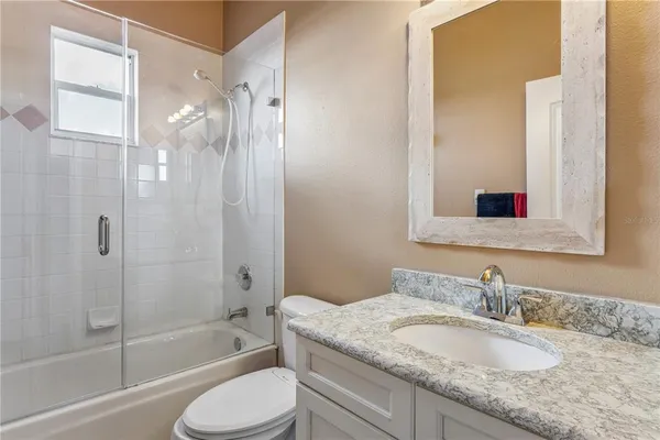 a bathroom with a granite countertop bathtub shower sink and toilet