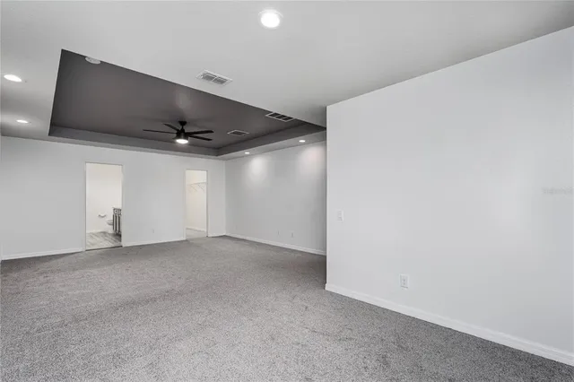 an empty room with ceiling fan and windows