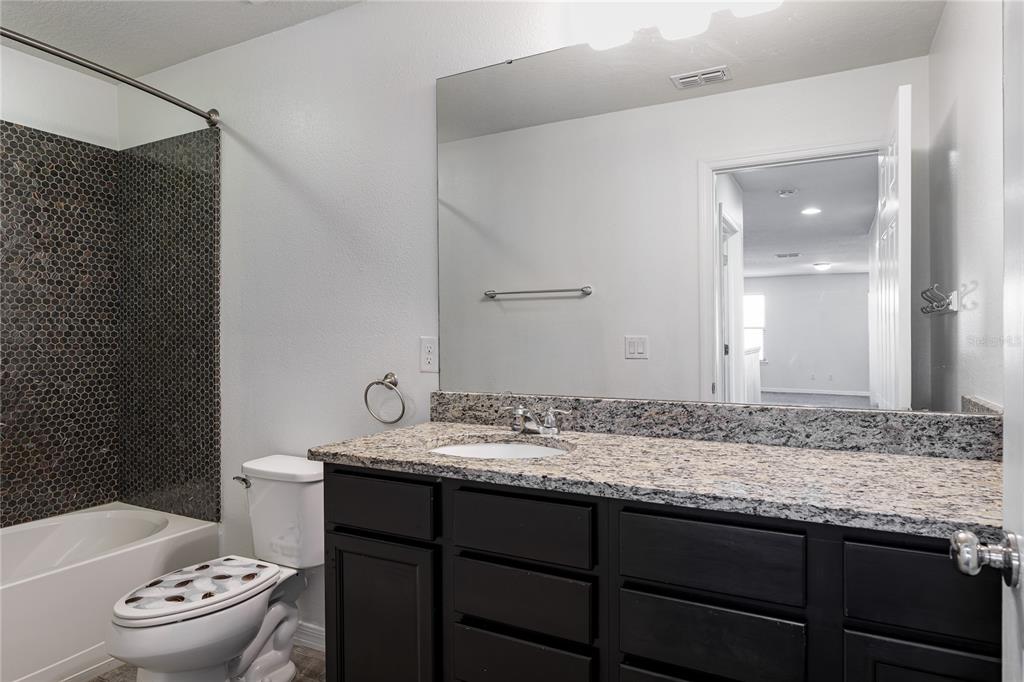 6026 100th Avenue East Parrish, FL 34219 - Photo 25 of 51 a bathroom with a granite countertop sink and a mirror with toilet
