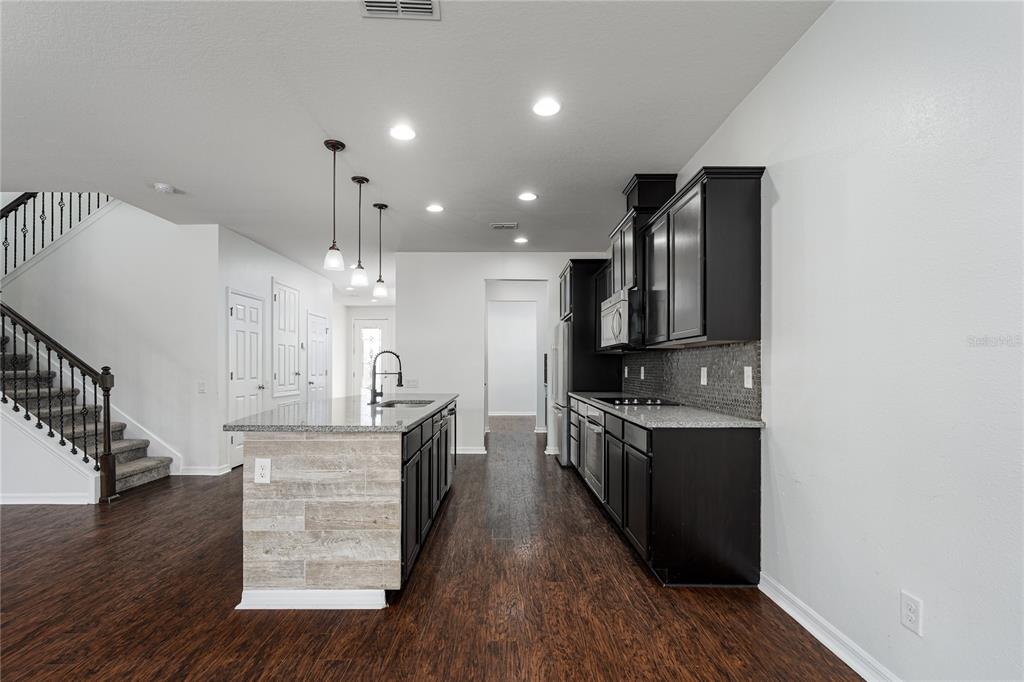 6026 100th Avenue East Parrish, FL 34219 - Photo 5 of 51 a large kitchen with stainless steel appliances granite countertop a stove and a wooden floors