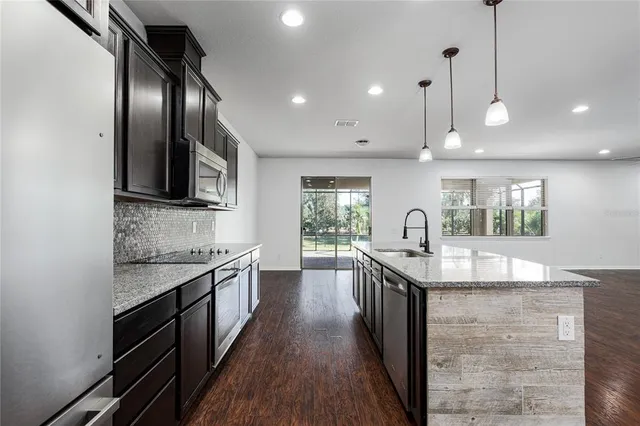 a kitchen with stainless steel appliances granite countertop a sink a stove and a wooden floors