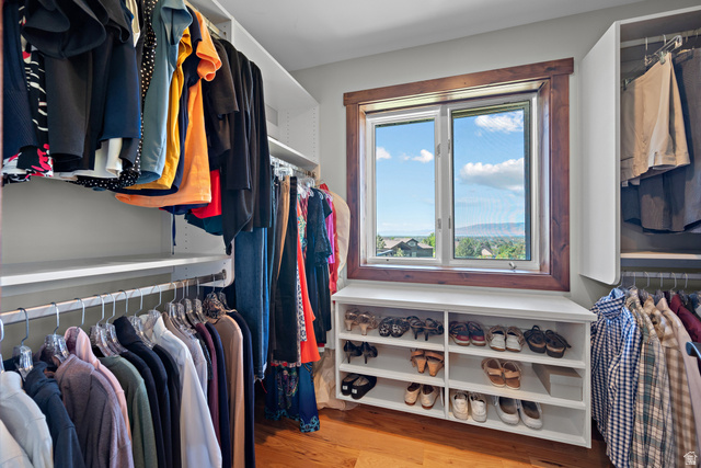 4221 Juniper Circle Alpine, UT 84004 - Photo 13 of 66 Custom walk-in closet featuring extensive built-in shelving and hanging rods, a built-in window seat with shoe storage, wood-finish flooring, and a large window with wood trim