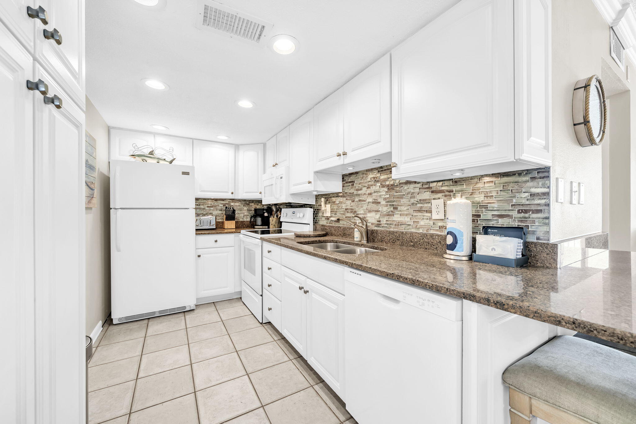 676 Santa Rosa Boulevard, Unit 5F Fort Walton Beach, FL 32548 - Photo 9 of 34 a kitchen with granite countertop a refrigerator a sink and white cabinets