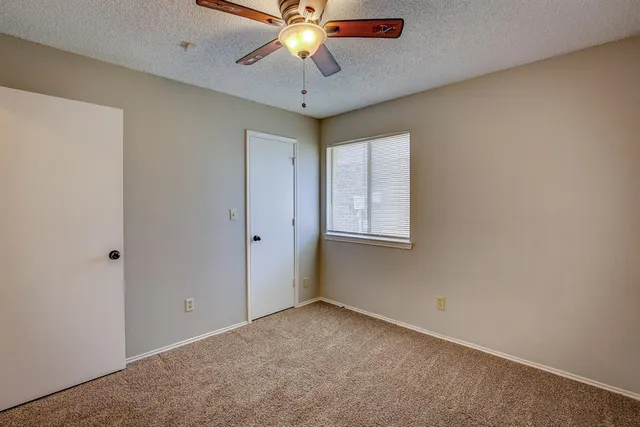 an empty room with a ceiling fan and carpet