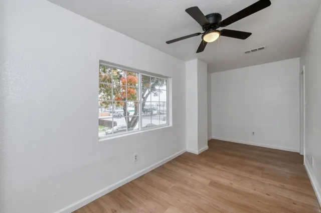 a view of empty room with wooden floor and fan
