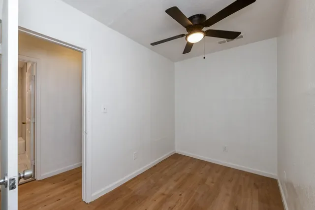 an empty room with wooden floor and ceiling fan