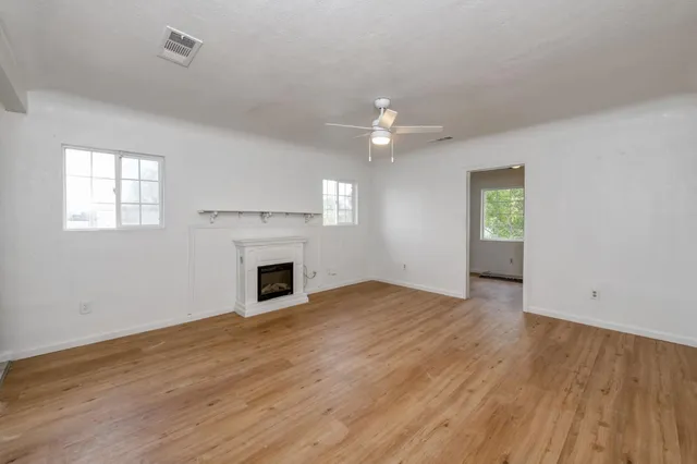 an empty room with windows fireplace and wooden floor