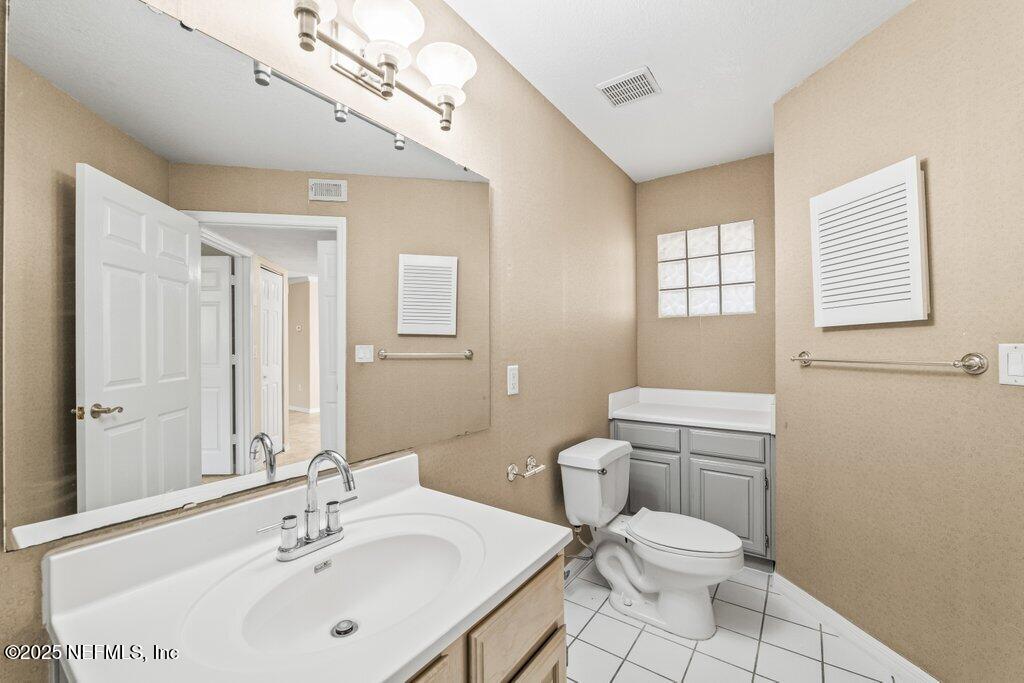 10150 Belle Rive Boulevard, Unit 303 Jacksonville, FL 32256 - Photo 12 of 23 a bathroom with a toilet a sink a mirror and a window