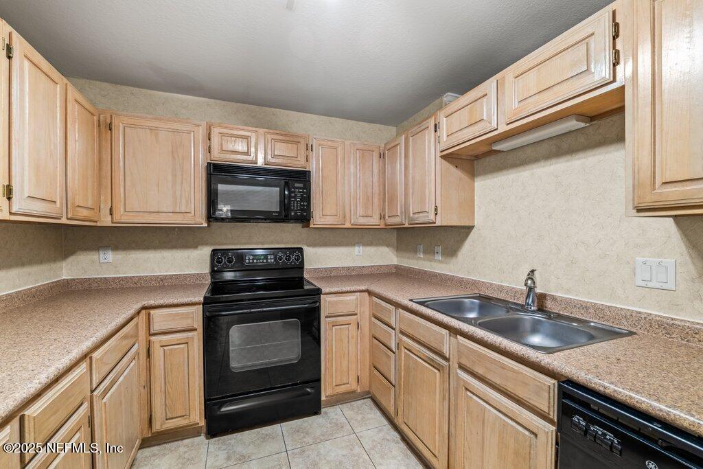 10150 Belle Rive Boulevard, Unit 303 Jacksonville, FL 32256 - Photo 7 of 23 a kitchen with granite countertop a sink dishwasher stove and microwave with wooden cabinets