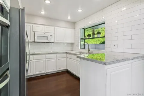 a kitchen with white cabinets and sink
