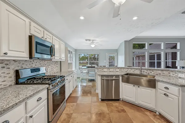 a kitchen with stainless steel appliances granite countertop a stove top oven a sink dishwasher and a microwave oven with white cabinets