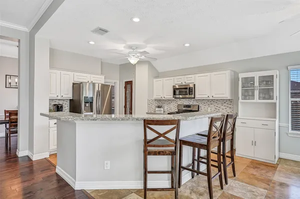 a kitchen with stainless steel appliances a dining table chairs refrigerator and microwave