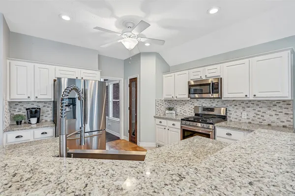 a kitchen with stainless steel appliances kitchen island granite countertop a refrigerator stove and sink