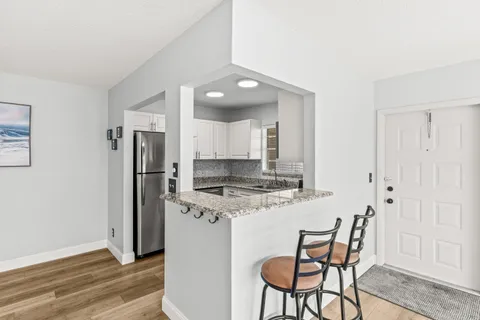 a kitchen with stainless steel appliances a stove refrigerator and chairs