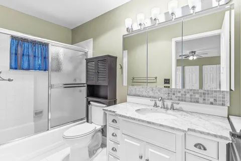 a bathroom with a granite countertop sink toilet and shower