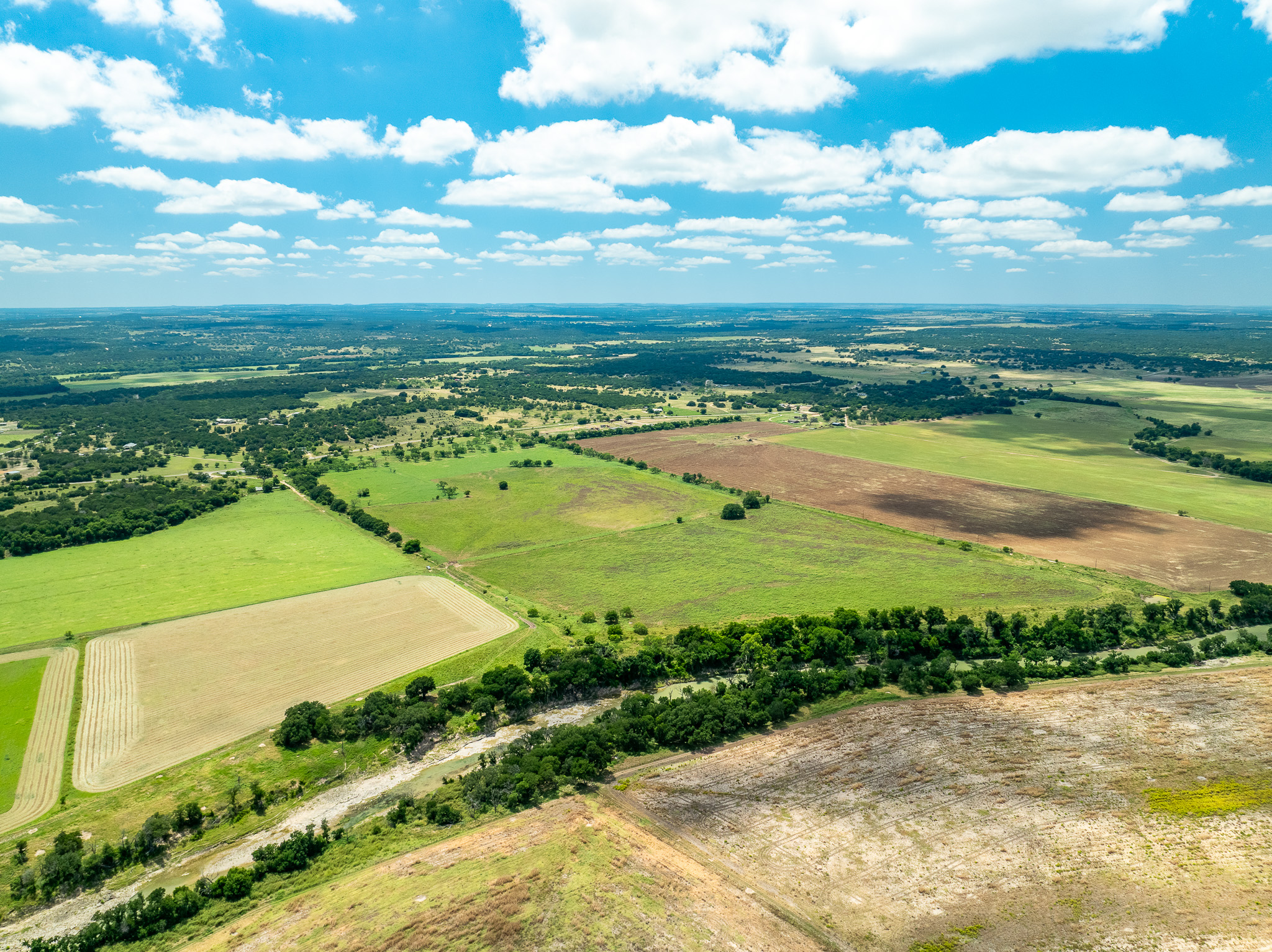 8044 580th Street East Kempner, TX 76539 - Photo 4 of 40 Vast fields and verdant woodlands extend beneath a clear blue sky, presenting an opportunity for serene rural living.