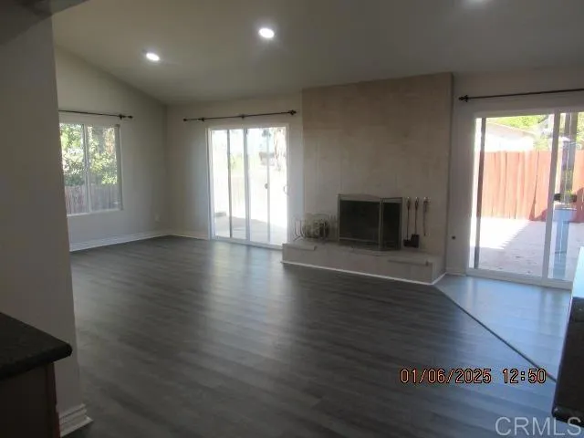 an empty room with wooden floor fireplace and windows