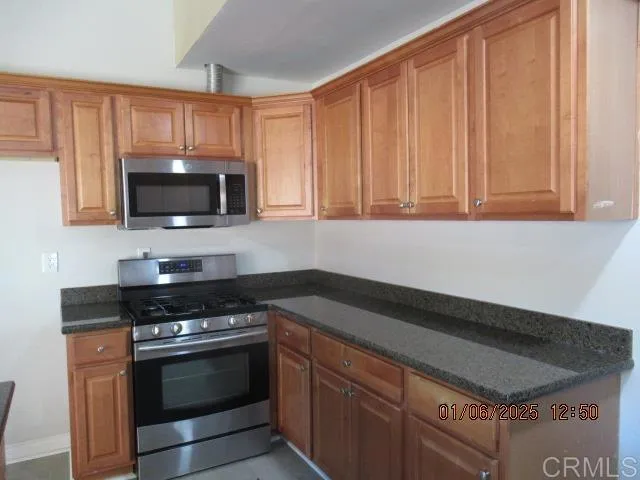 a kitchen with granite countertop a stove and a microwave