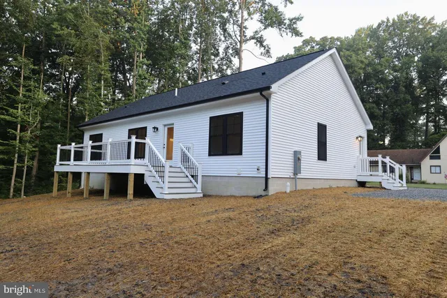 a front view of house with yard and trees in the background
