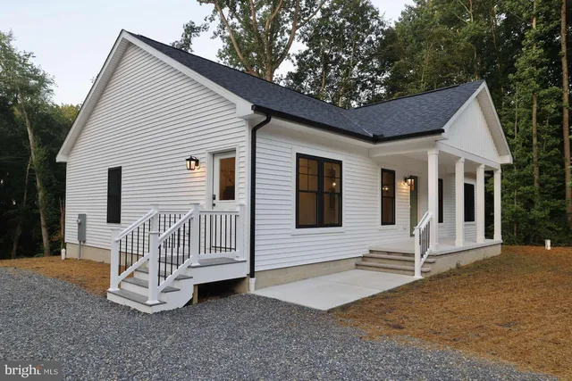 a white house with a small yard and large tree