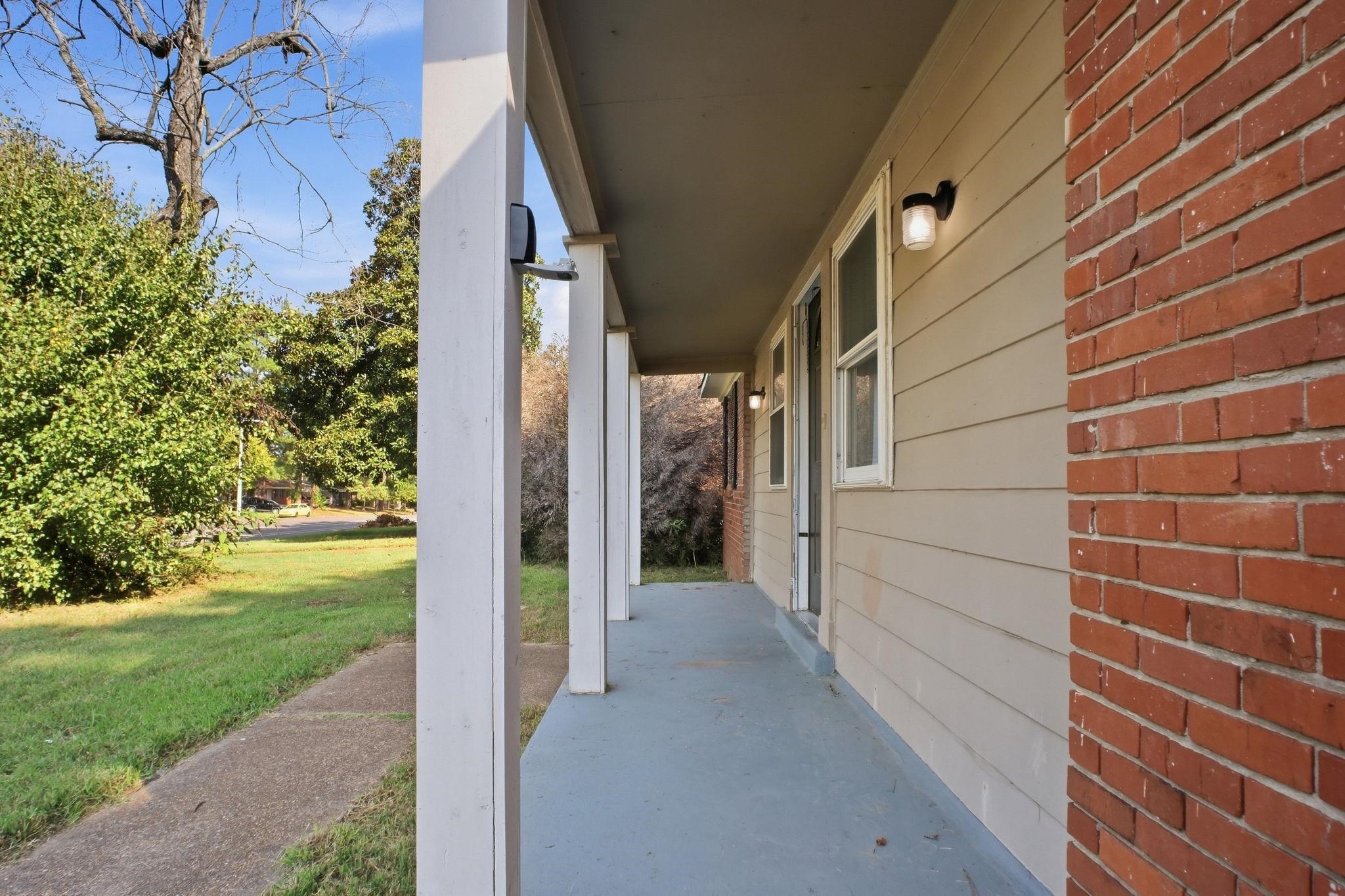 4562 Tulane Road Memphis, TN 38109 - Photo 4 of 32 Covered porch with painted concrete flooring, white support columns, horizontal siding, and brick facade