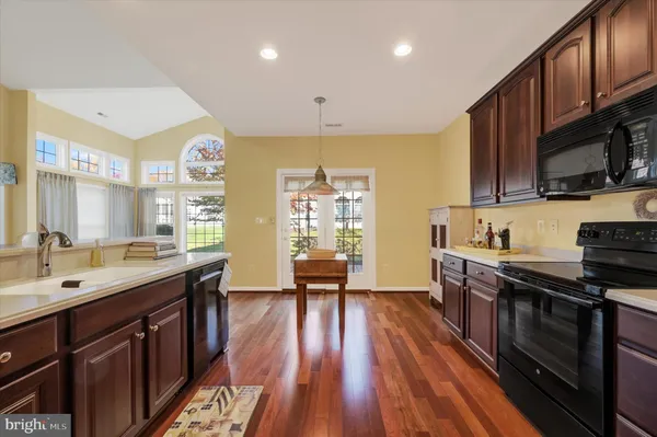 a large kitchen with stainless steel appliances granite countertop a lot of counter space and wooden floors
