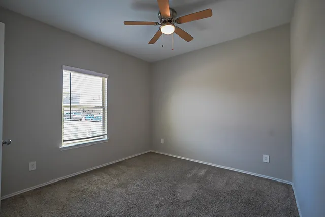an empty room with a window and a fan