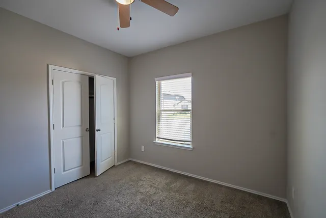 an empty room with windows and chandelier fan