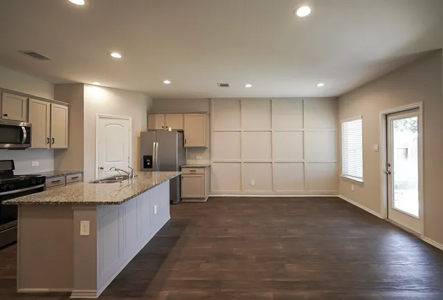 a large kitchen with stainless steel appliances granite countertop a large counter top a sink and a refrigerator