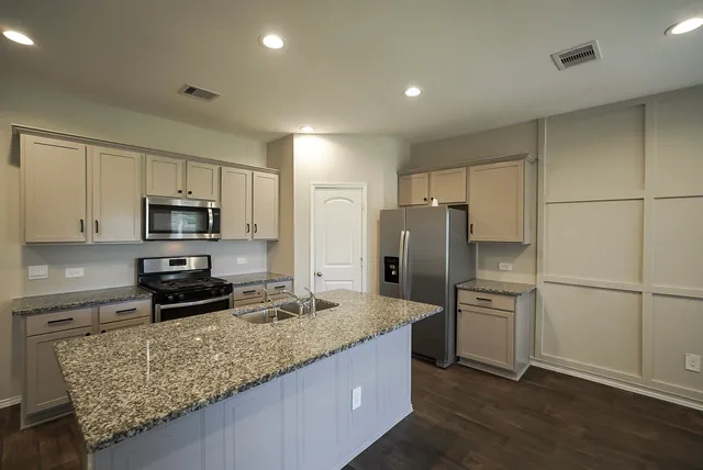 a kitchen with granite countertop a refrigerator and a sink