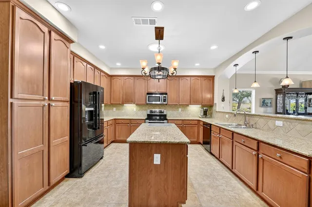 a large kitchen with stainless steel appliances kitchen island granite countertop a refrigerator a sink dishwasher with a dining table and chairs