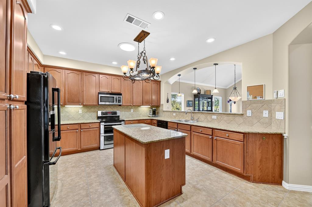 9813 Callaway Court Denton, TX 76207 - Photo 15 of 39 a kitchen with stainless steel appliances granite countertop a sink stove and refrigerator