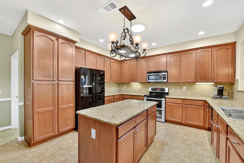 9813 Callaway Court Denton, TX 76207 - Photo 16 of 39 a kitchen with a refrigerator a sink and cabinets