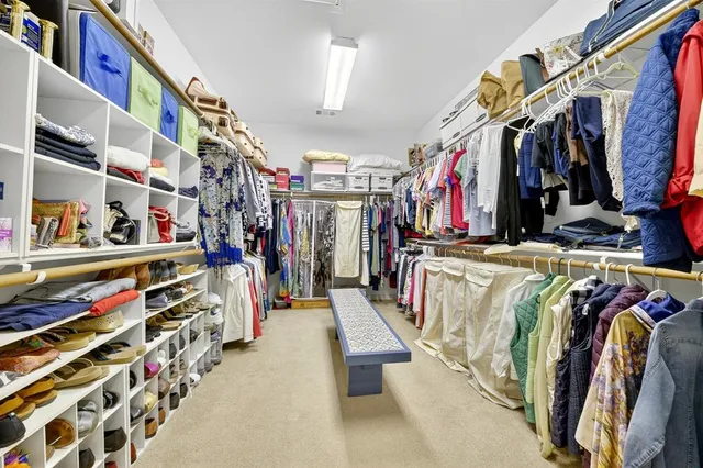 a view of walk in closet with clothes and shoes