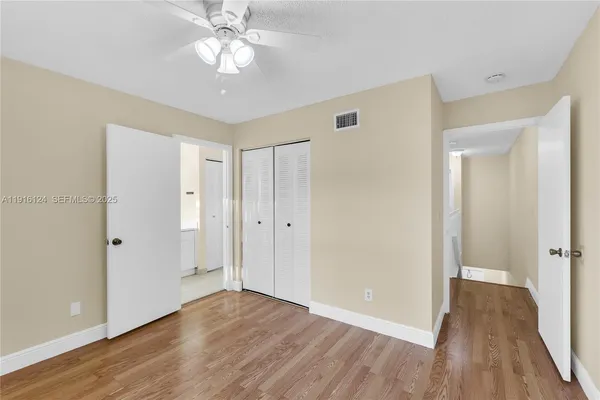 an empty room with wooden floor and fan