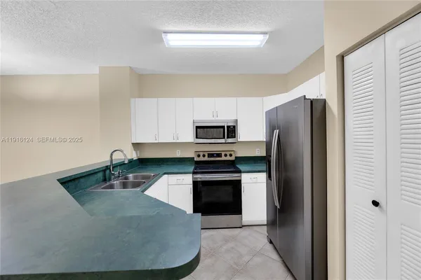 a kitchen with stainless steel appliances granite countertop a refrigerator a stove and a sink with wooden floor