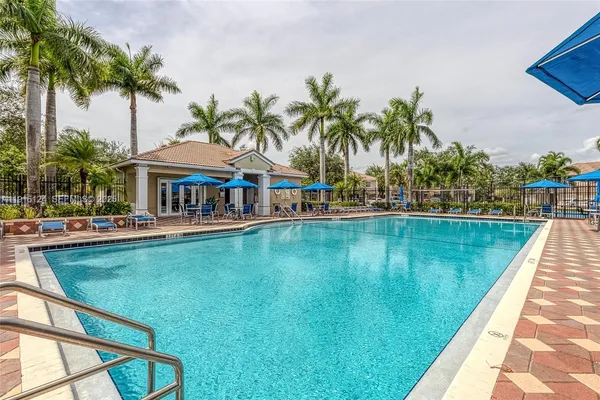 a view of swimming pool with lawn chairs under an umbrella