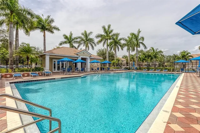 a view of swimming pool with lawn chairs under an umbrella
