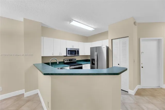 a kitchen with stainless steel appliances granite countertop a refrigerator a stove a sink and white cabinets